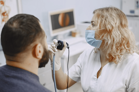 medica realiza exame de laringoscopia com biopsia em paciente homem em consultorio