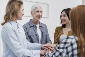 Um grupo de mulheres, de diferentes idades, unidas em um momento de apoio mútuo e celebração, representando a força das redes de apoio. Essa união reflete o compromisso do Instituto da Tireoide & Laringe em fornecer uma abordagem humanizada e colaborativa no atendimento, tanto para os pacientes quanto para seus familiares.